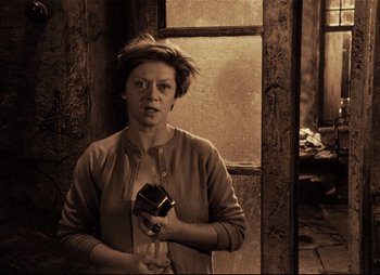 Movie still from “Stalker” (1979), directed by Andrei Tarkovsky – A person holding a cell phone in a room; Medium shot, High angle
