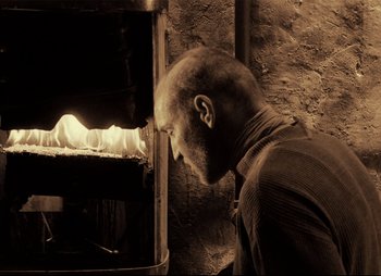 Movie still from “Stalker” (1979), directed by Andrei Tarkovsky – A man looking into an oven with a beard; Medium shot, Low angle