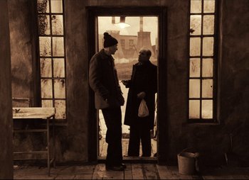 Movie still from “Stalker” (1979), directed by Andrei Tarkovsky – Two people standing in front of a door; Wide shot, Over the shoulder angle