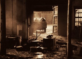 Movie still from “Stalker” (1979), directed by Andrei Tarkovsky – An old truck is parked in a dirty garage; Wide shot, High angle