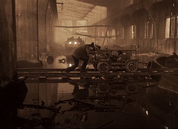 Movie still from “Stalker” (1979), directed by Andrei Tarkovsky – A man working on a train track in an industrial setting; Extreme Wide shot, High angle