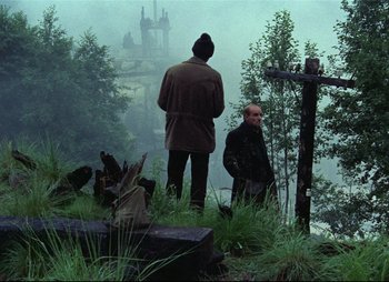 Movie still from “Stalker” (1979), directed by Andrei Tarkovsky – Two men standing on a hill near a cross; Wide shot, High angle