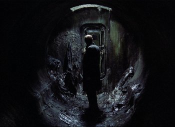 Movie still from “Stalker” (1979), directed by Andrei Tarkovsky – A man standing inside of an underground tunnel; Wide shot, High angle
