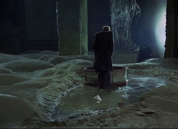 Movie still from “Stalker” (1979), directed by Andrei Tarkovsky – A man standing in the middle of a pool of water; Wide shot, High angle