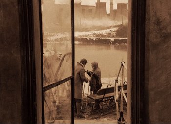 Movie still from “Stalker” (1979), directed by Andrei Tarkovsky – Two people sitting on a bench in front of a river; Wide shot, High angle