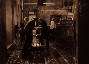 Movie still from “Stalker” (1979), directed by Andrei Tarkovsky – A group of people standing around a table in a room; Wide shot, High angle