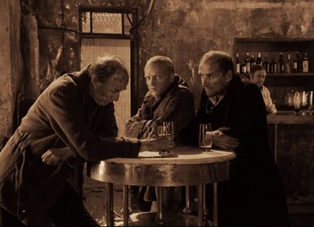 Movie still from “Stalker” (1979), directed by Andrei Tarkovsky – A group of men sitting at a table with drinks; Wide shot, High angle