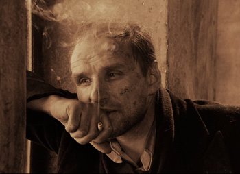 Movie still from “Stalker” (1979), directed by Andrei Tarkovsky – A man smoking a cigarette while wearing a robe; Close Up shot, Low angle