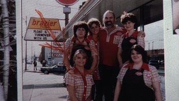 Movie still from “Star 80” (1983), directed by Bob Fosse – A group of people that are standing in front of a building; Wide shot, High angle