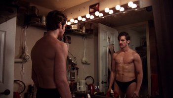 Movie still from “Star 80” (1983), directed by Bob Fosse – A man in black underwear looking at himself in a mirror; Medium shot, Over the shoulder angle