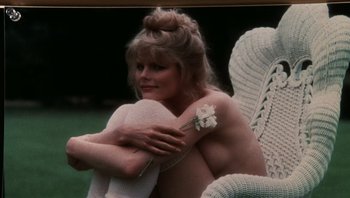 Movie still from “Star 80” (1983), directed by Bob Fosse – A woman sitting in a chair with a flower in her hand; Medium shot, High angle