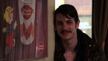 Movie still from “Star 80” (1983), directed by Bob Fosse – A man with a mustache standing next to a dairy queen poster; Close Up shot, Over the shoulder angle