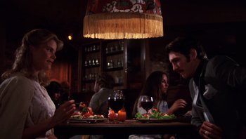 Movie still from “Star 80” (1983), directed by Bob Fosse – A group of people sitting at a table with food; Medium shot, Low angle