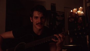 A man holding a guitar in a dark room