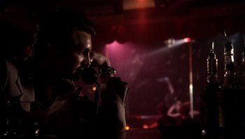 Movie still from “Star 80” (1983), directed by Bob Fosse – A man holding a phone up to his ear while sitting at a bar; Close Up shot, Low angle