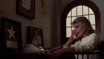 Movie still from “Star 80” (1983), directed by Bob Fosse – A woman sitting at a desk talking on the phone; Medium shot, Low angle