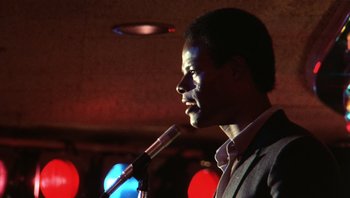 Movie still from “Star 80” (1983), directed by Bob Fosse – A man is speaking into a microphone in front of a crowd; Close Up shot, Low angle