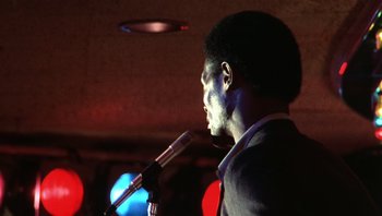 Movie still from “Star 80” (1983), directed by Bob Fosse – A man is speaking into a microphone in front of a crowd; Close Up shot, Low angle
