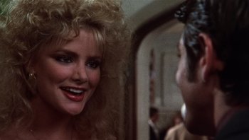 Movie still from “Star 80” (1983), directed by Bob Fosse – A woman smiles at the camera while a man looks on; Close Up shot, Over the shoulder angle