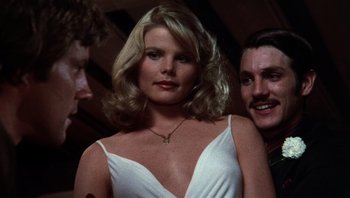 Movie still from “Star 80” (1983), directed by Bob Fosse – A woman in a white dress standing next to two other men; Close Up shot, Low angle