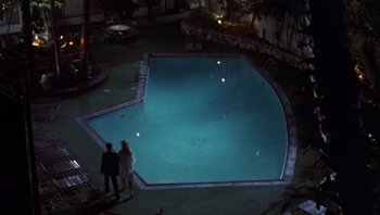Movie still from “Star 80” (1983), directed by Bob Fosse – Two people standing next to a pool at night; Extreme Wide shot, High angle