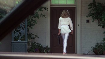Movie still from “Star 80” (1983), directed by Bob Fosse – A woman in a white outfit walking out of a house; Wide shot, Low angle