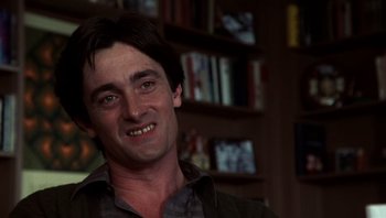 Movie still from “Star 80” (1983), directed by Bob Fosse – A person smiling with a book shelf in the background; Close Up shot, Low angle