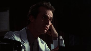 Movie still from “Star 80” (1983), directed by Bob Fosse – A man wearing a lab coat sitting in front of a mirror; Close Up shot, Low angle