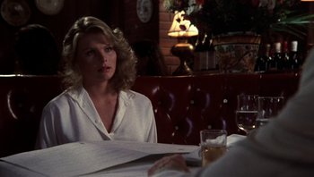 Movie still from “Star 80” (1983), directed by Bob Fosse – A woman sitting at a table in front of a glass of wine; Close Up shot, Over the shoulder angle