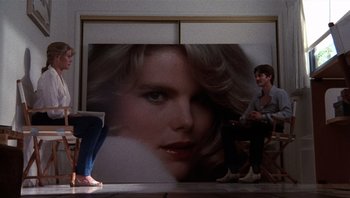 Movie still from “Star 80” (1983), directed by Bob Fosse – A woman sitting in front of a picture of a man; Wide shot, Over the shoulder angle