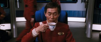 Movie still from “Star Trek VI: The Undiscovered Country” (1991), directed by Nicholas Meyer – A man sitting down drinking a cup of coffee; Close Up shot, Over the shoulder angle