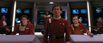 Movie still from “Star Trek VI: The Undiscovered Country” (1991), directed by Nicholas Meyer – A group of people in a room with a red uniform on them; Medium shot, Over the shoulder angle