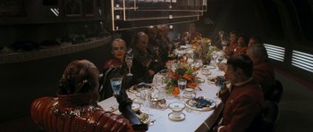 Movie still from “Star Trek VI: The Undiscovered Country” (1991), directed by Nicholas Meyer – A group of people sitting at a table with food and drinks; Wide shot, High angle