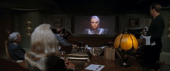 Movie still from “Star Trek VI: The Undiscovered Country” (1991), directed by Nicholas Meyer – A group of people sitting at a table watching a movie on a projector screen; Medium shot, Over the shoulder angle