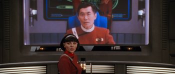 Movie still from “Star Trek VI: The Undiscovered Country” (1991), directed by Nicholas Meyer – A woman standing in front of a screen with a star trek picture on it; Medium shot, Over the shoulder angle