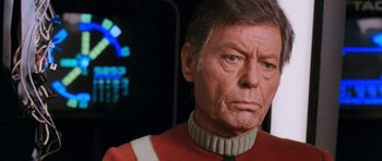 Movie still from “Star Trek VI: The Undiscovered Country” (1991), directed by Nicholas Meyer – An older man wearing a red and white uniform; Close Up shot, Over the shoulder angle