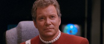Movie still from “Star Trek VI: The Undiscovered Country” (1991), directed by Nicholas Meyer – An older man wearing a red shirt and a white collar; Close Up shot, Over the shoulder angle
