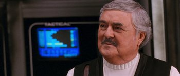 Movie still from “Star Trek VI: The Undiscovered Country” (1991), directed by Nicholas Meyer – An older man with a mustache looking at the camera; Close Up shot, Over the shoulder angle
