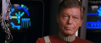 Movie still from “Star Trek VI: The Undiscovered Country” (1991), directed by Nicholas Meyer – An older man wearing a red and white uniform; Close Up shot, Over the shoulder angle