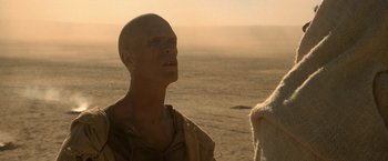 Movie still from “Star Trek V: The Final Frontier” (1989), directed by William Shatner – A bald man standing on the beach looking up at the sky; Close Up shot, Low angle