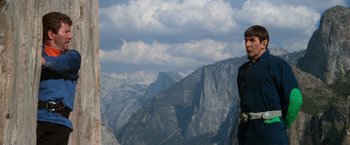 Movie still from “Star Trek V: The Final Frontier” (1989), directed by William Shatner – A man standing on top of a mountain looking at the camera; Medium shot, Low angle