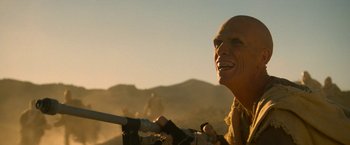 Movie still from “Star Trek V: The Final Frontier” (1989), directed by William Shatner – A man with a shaved head holding a gun in the desert; Close Up shot, Low angle