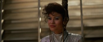 Movie still from “Star Trek V: The Final Frontier” (1989), directed by William Shatner – A woman wearing a silver top and headphones on top of her head; Close Up shot, Over the shoulder angle