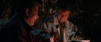 Movie still from “Star Trek V: The Final Frontier” (1989), directed by William Shatner – Two men sitting at a table with a bottle; Medium shot, Over the shoulder angle