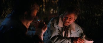 Movie still from “Star Trek V: The Final Frontier” (1989), directed by William Shatner – A man sitting next to another man with a cell phone in front of him; Close Up shot, Over the shoulder angle