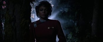 Movie still from “Star Trek V: The Final Frontier” (1989), directed by William Shatner – A woman in a red dress standing next to a tree; Close Up shot, Low angle