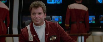 Movie still from “Star Trek V: The Final Frontier” (1989), directed by William Shatner – A man in a red jacket is sitting in front of a computer screen; Close Up shot, Over the shoulder angle