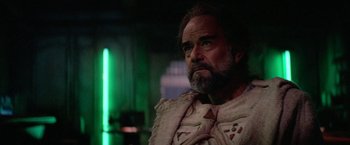 Movie still from “Star Trek V: The Final Frontier” (1989), directed by William Shatner – A man with long hair and a beard is looking to his left; Close Up shot, Over the shoulder angle