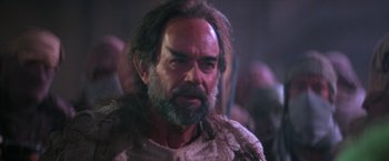 Movie still from “Star Trek V: The Final Frontier” (1989), directed by William Shatner – A man with long hair and a beard is looking at the camera; Close Up shot, Over the shoulder angle