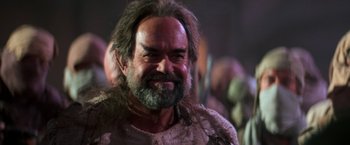 Movie still from “Star Trek V: The Final Frontier” (1989), directed by William Shatner – A man with long hair and a beard smiling for the camera; Close Up shot, Over the shoulder angle